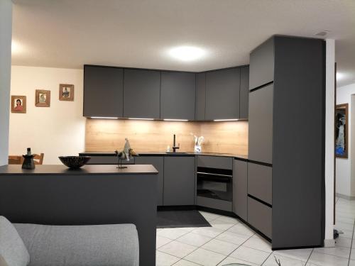 een keuken met zwarte kasten en een keukeneiland bij Ferienwohnung Paradiso 1 in Grächen