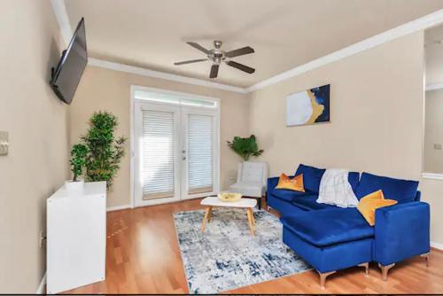 a living room with a blue couch and a ceiling fan at Modern Medical Center Condo near MD Anderson & NRG in Houston