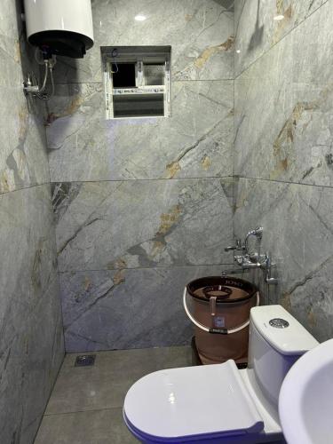 a bathroom with a toilet and a window at Breezy bluff in Madikeri