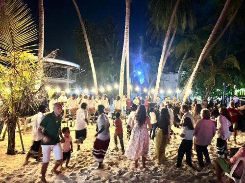 een menigte mensen die 's nachts over het strand loopt bij Madi Beach Guesthouse in Maalhos