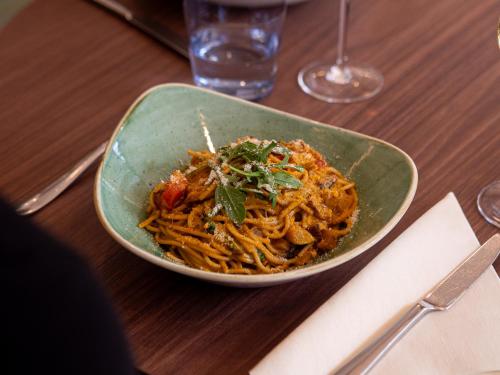 una ciotola di spaghetti su un tavolo di legno di Hilton Garden Inn Munich Messe a Feldkirchen