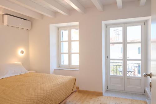 a white bedroom with a bed and a window at Galaxidaki στην Πλατεία in Galaxidi
