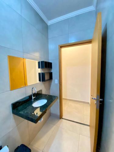 a bathroom with a sink and a mirror and a door at Suítes Itapoã in Ubatuba