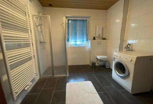 a bathroom with a washing machine and a toilet at Ferienhaus Seestern in Dornum