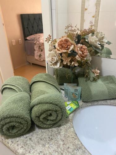 a bathroom with green towels and a sink and a mirror at Quarto suíte privativa in Xaxim