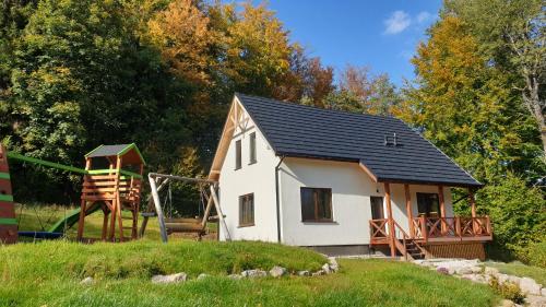 a small white house with a playground in a yard at Omszałe Głazy Dom i Domek na wyłączność przy szlakach Karkonoszy in Zachełmie