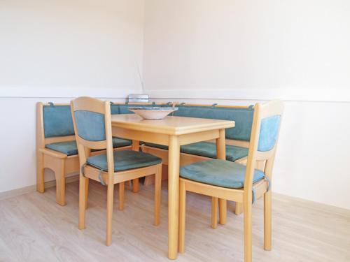 a wooden table with four chairs and a bowl on it at Haus Strandkrabbe, Seehund in Döse