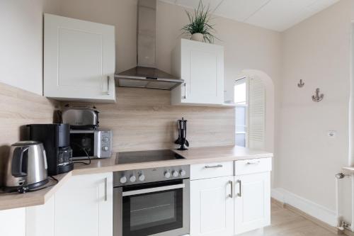 a kitchen with white cabinets and a stove top oven at Haus Strandkrabbe, Seehund in Döse