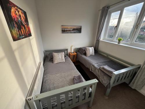 a bedroom with two beds and a window at Stylish modern Cottage, Kidderminster in Kidderminster