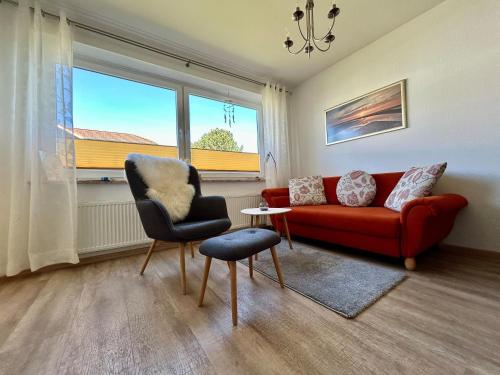a living room with a red couch and a chair at Haus Vogelsand, App 324 in Cuxhaven