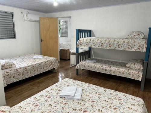 a room with two beds and a bunk bed with a table at Canto do viajante in São Gabriel
