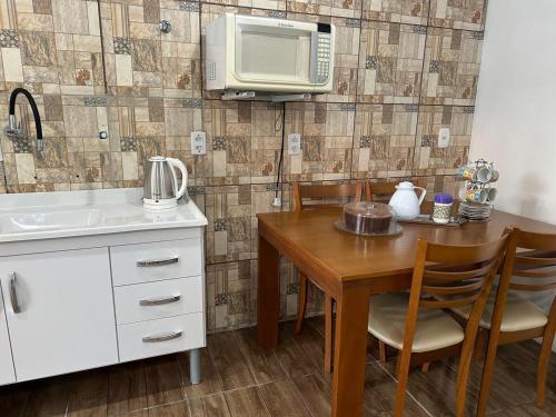 a kitchen with a wooden table and a microwave at Canto do viajante in São Gabriel