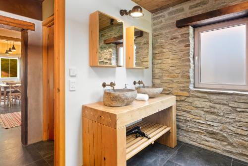 a bathroom with two sinks and a stone wall at Stone Cottage in Arrowtown