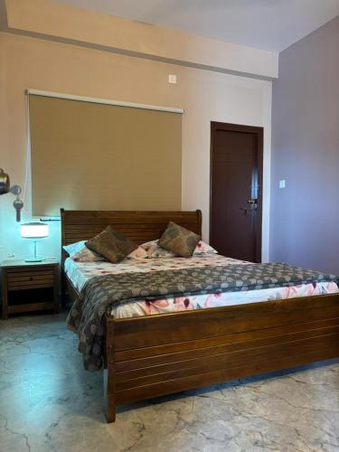 a bedroom with a wooden bed with a lamp and a table at Villa Vista in Mysore