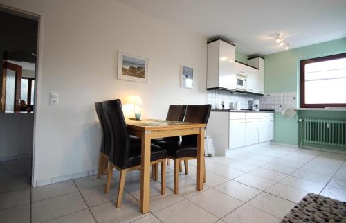 a kitchen with a wooden table and black chairs at Haus Seehund, Whg 13 in Cuxhaven