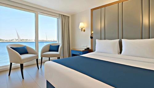 a hotel room with a bed and two chairs at Five-Star Deluxe River Kruz from Aswan to Luxor 3 Nights in Aswān