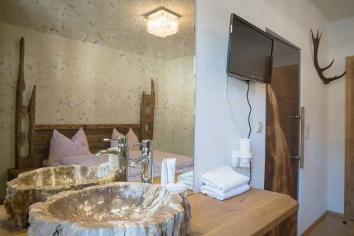 a bathroom with two sinks and a tv on the wall at Atelier Garni Astei in Grossarl