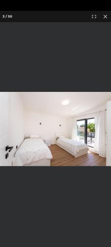 a white bedroom with a bed and a window at Petra in Biograd na Moru
