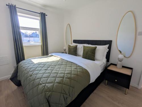 a bedroom with a large bed with two mirrors at Saffron Court Apartments in High Wycombe