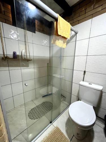 a bathroom with a toilet and a glass shower at Sítio Araripe Eco House in Santa Cruz Cabrália