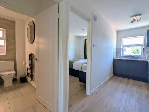 a bedroom with a bed and a bathroom with a sink at Saffron Court Apartments in High Wycombe