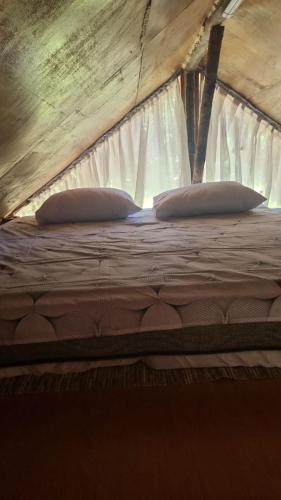 a bed with two pillows on top of it at Sítio Araripe Eco House in Santa Cruz Cabrália