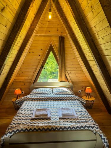 a large bed in a wooden room with a window at Mountain Houses Emilija in Žabljak