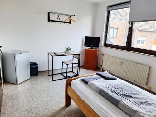 a bedroom with a bed and a table and a window at Gästezimmer B in Mönchengladbach