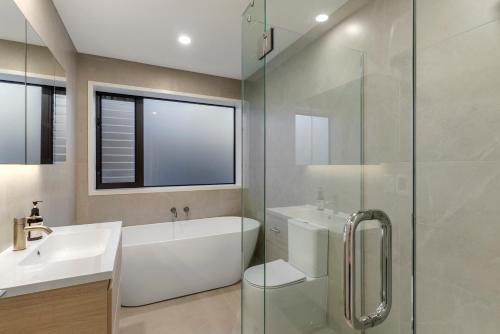 a bathroom with a tub and a sink and a shower at Stylish Townhouse in Auckland