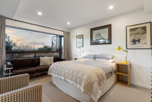 a bedroom with a bed and a couch and a window at Stylish Townhouse in Auckland