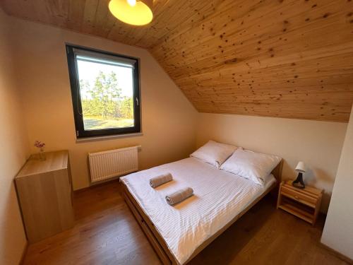 een slaapkamer met een bed in een kamer met een raam bij Domki Gorąca Bania in Gowidlino