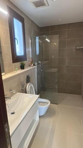 a bathroom with a sink and a shower and a toilet at Cosy 1BR with a PUBLIC POOL and WIFI in Ma‘mūrah