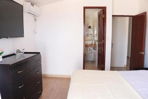 una camera con letto e comò con TV a schermo piatto di Casa del Mar Malin a Ballenita