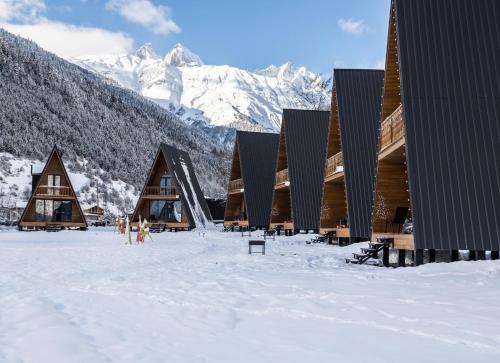 a group of buildings in the snow with mountains at Winterfell Mestia - Premium Chalet Complex & SPA in Mestia