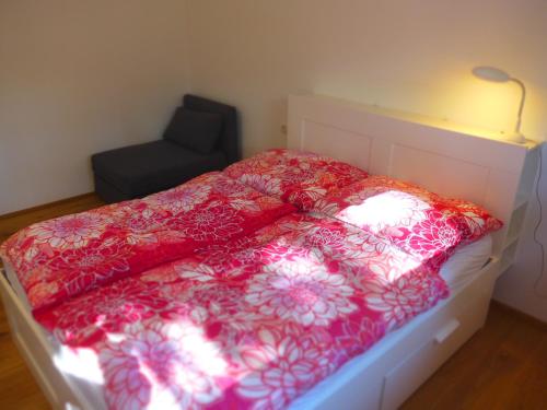 a bed with a red comforter and a chair at green Home - Sonniges Chalet in den Alpen in Kirchberg in Tirol