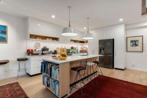 a kitchen with white cabinets and a island with bar stools at Stylish Townhouse in Auckland