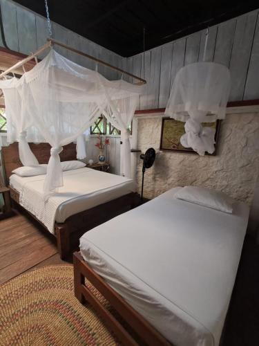 a bedroom with two beds with white sheets at Maloka Napü - Ecodestinos in Puerto Nariño