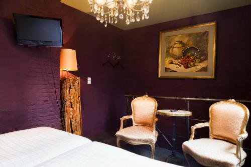 a bedroom with a bed and two chairs and a tv at Hotel Diamonds and Pearls in Antwerp