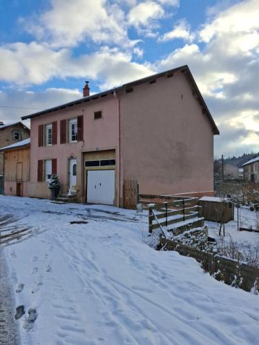 a pink building with a garage in the snow at Maison familiale en lisière de forêt in Val-et-Châtillon