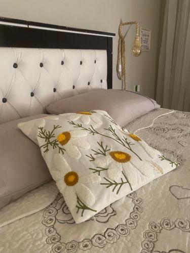 a bed with a pillow with flowers on it at Suíte privativa quarto in Xaxim