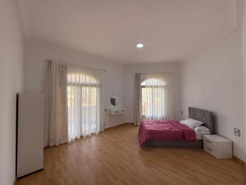 a white bedroom with a bed and two windows at Almajidy Villa in Cairo