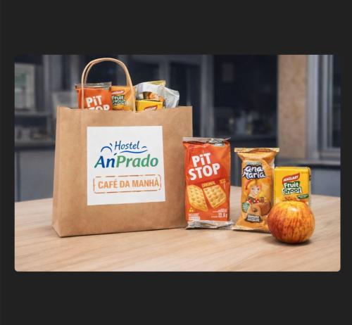 a paper bag and some snacks and an apple on a table at Hostel Anprado #3 Kit café incluso, Próx-Aeroporto de Guarulhos in Guarulhos