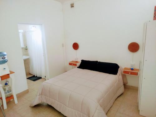a white bedroom with a bed and a bathroom at La Esquina de Norma in General Villegas