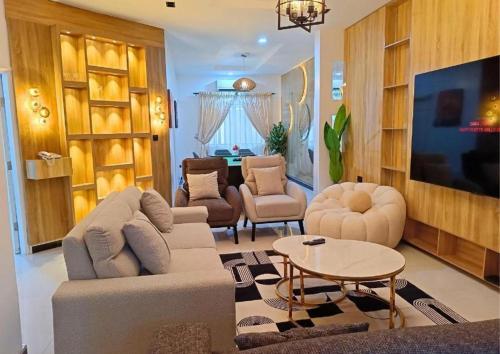 un soggiorno con divano, sedie e TV di Signature Apartments a Warri
