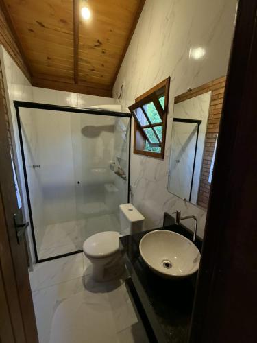 a bathroom with a toilet and a sink and a shower at Pousada Casa do Geninho in Conceição da Ibitipoca