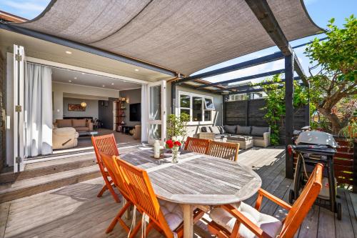 a patio with a table and chairs and a grill at Silver Seas Retreat in Muriwai Beach