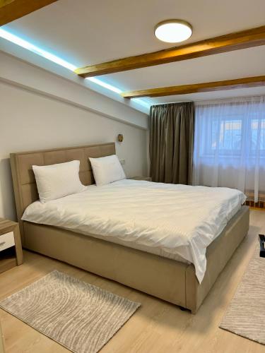 a bedroom with a large bed with white sheets at Parc Vatra Dornei - The 7th Haven in Vatra Dornei