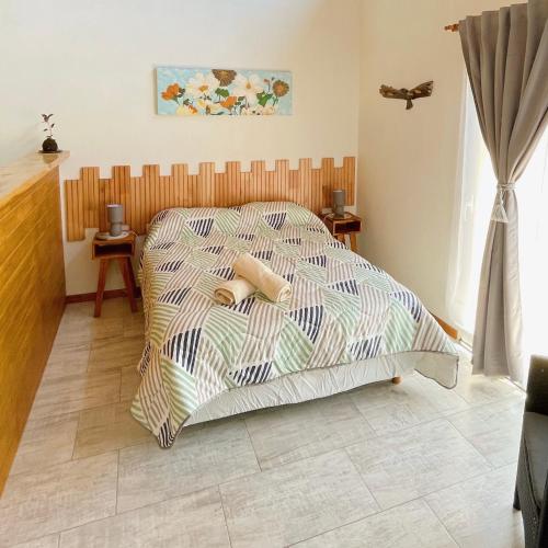 a bedroom with a bed with a comforter at Los Nenúfares in Lago Puelo