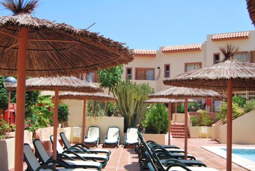 a row of chairs and umbrellas next to a pool at Albir Hills Apartments in Albir