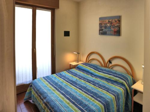 - une chambre avec un lit et une couverture rayée colorée dans l'établissement Salisburgo, à Lignano Sabbiadoro